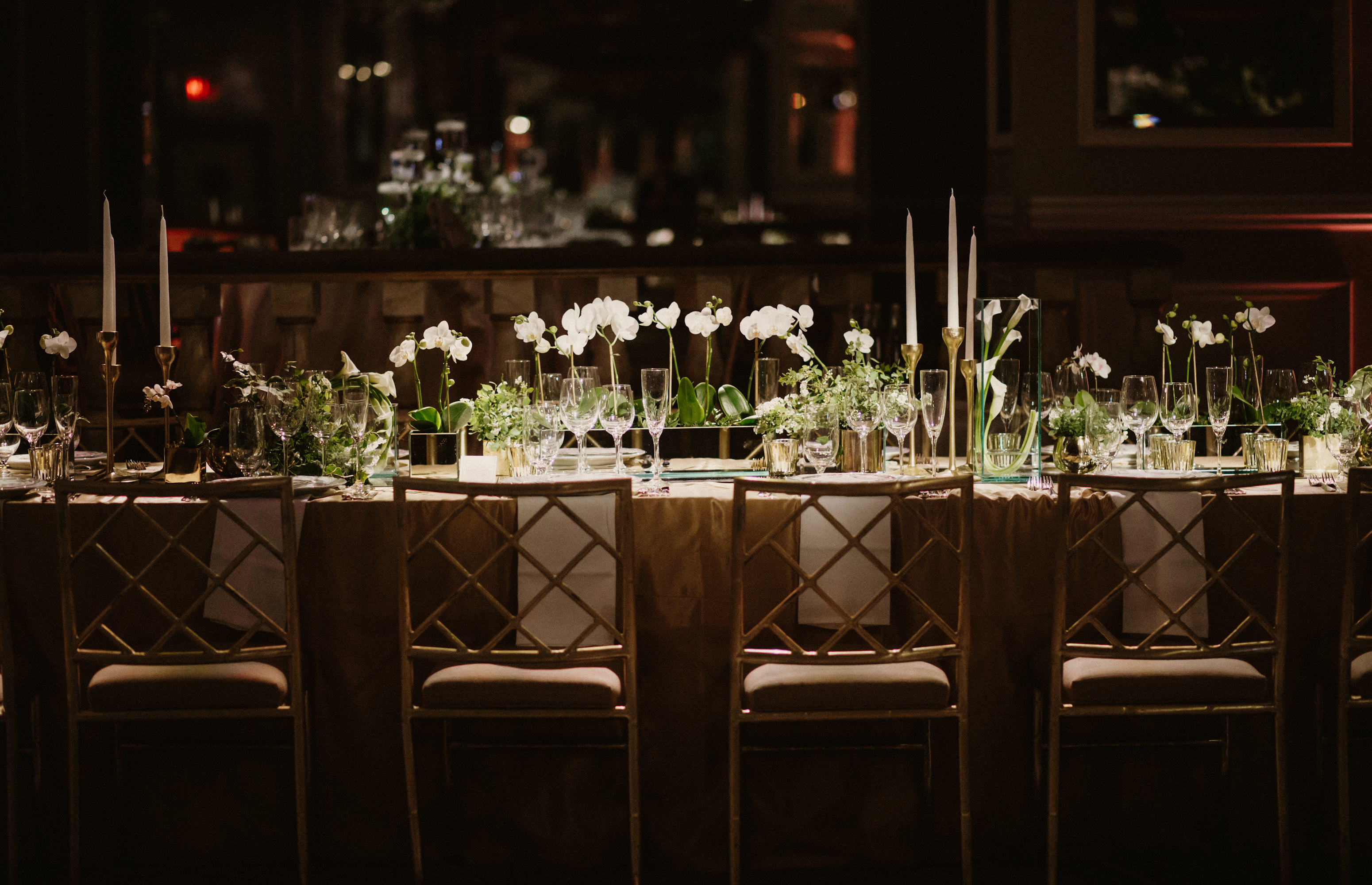 Table de banquet de mariage élégante avec nappage doré, chaises assorties, bougies blanches et compositions d'orchidées - Sainte Harmonie, Baijiu Français.
