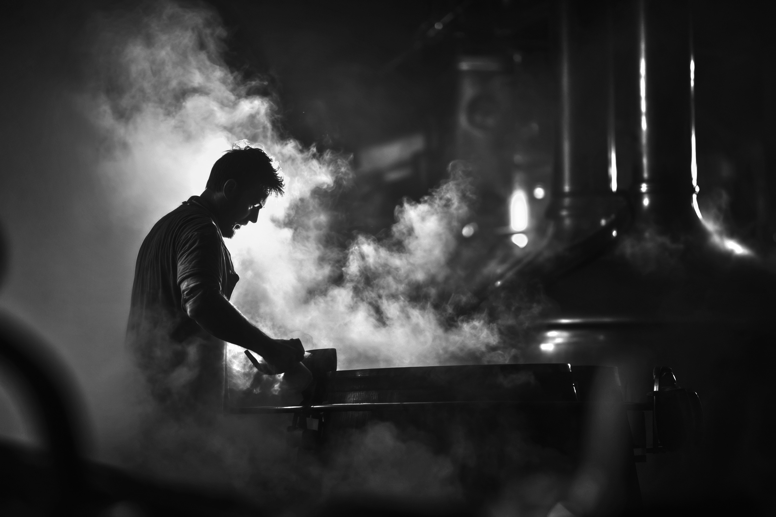 Silhouette en noir et blanc d'un artisan distillateur enveloppé de vapeur dense pendant le processus de distillation traditionnelle - Sainte Harmonie, Baijiu Français.